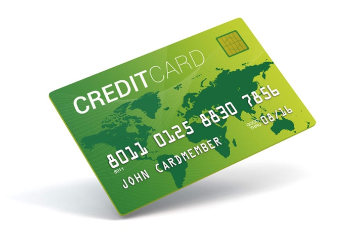 A green credit card with a picture of a world map in the background.